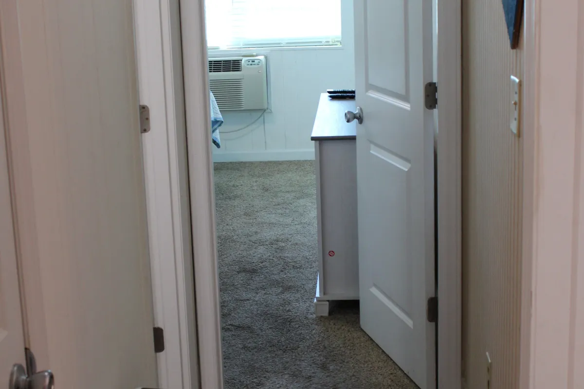 A calm nook with an open door leading to another part of the condo, a desk, and an air conditioning unit. The setup suggests a flexible space for reading, working, or unwinding, and the open door hints at connectivity with the rest of the home or the outside world.